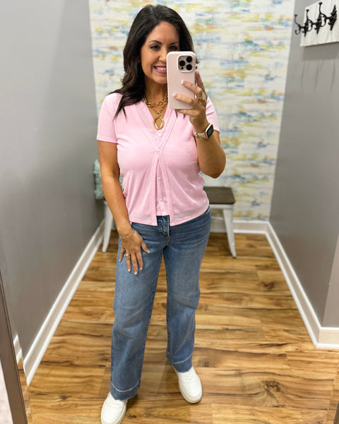 woman wearing pink top, risen straight jeans, gold chunky necklace and white sneakers