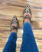 Leopard print shoes with pink interior on a wooden floor