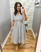 Woman wearing a striped dress in a room with a patterned wall.