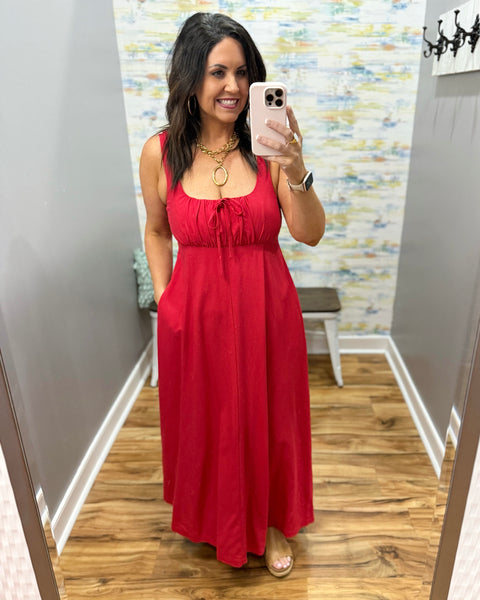 Woman wearing a red dress in a room with a patterned wall.