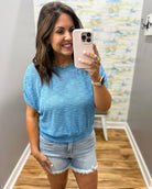woman wearing a blue top with denim shorts.