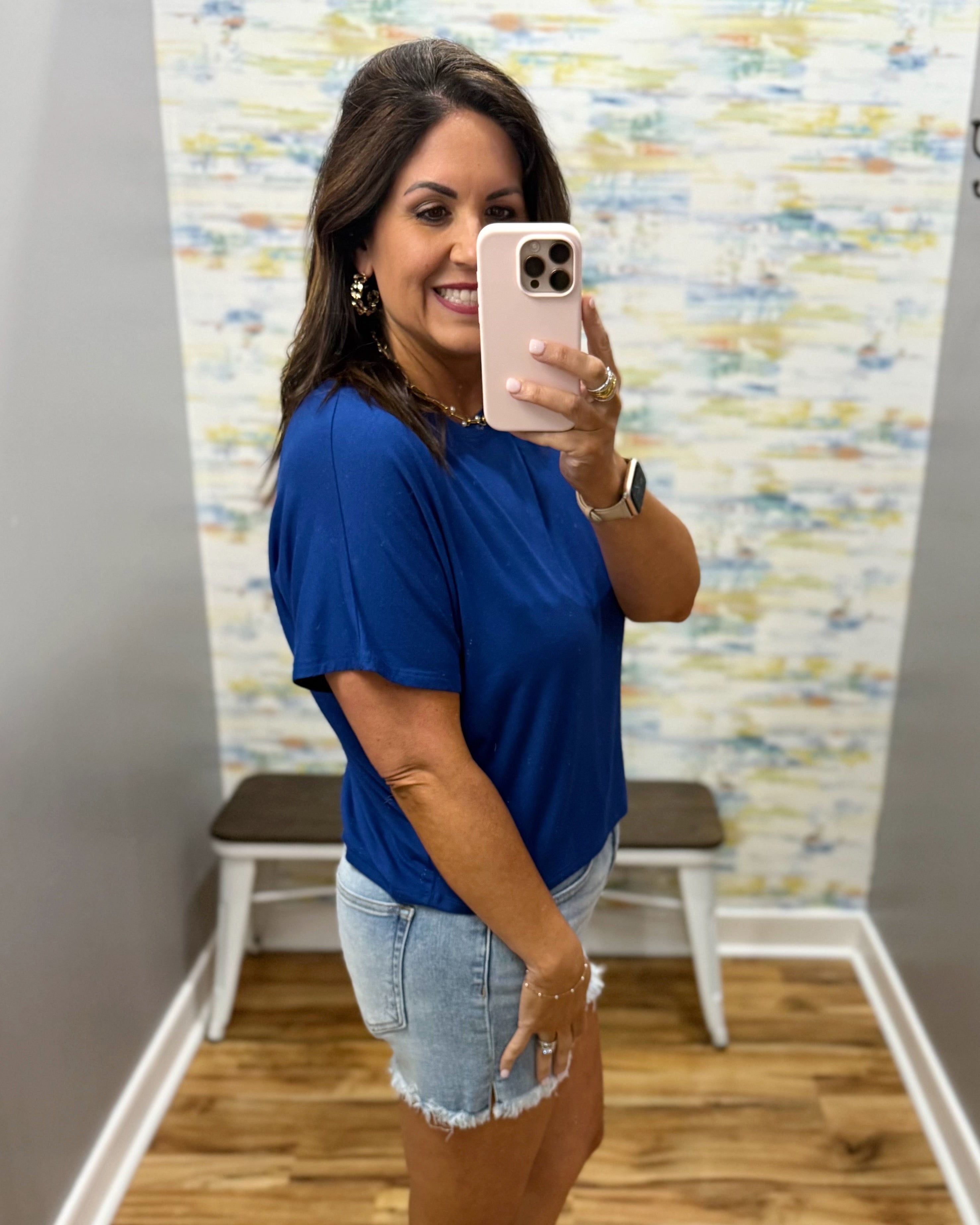 woman wearing blue t-shirt top with denim shorts.