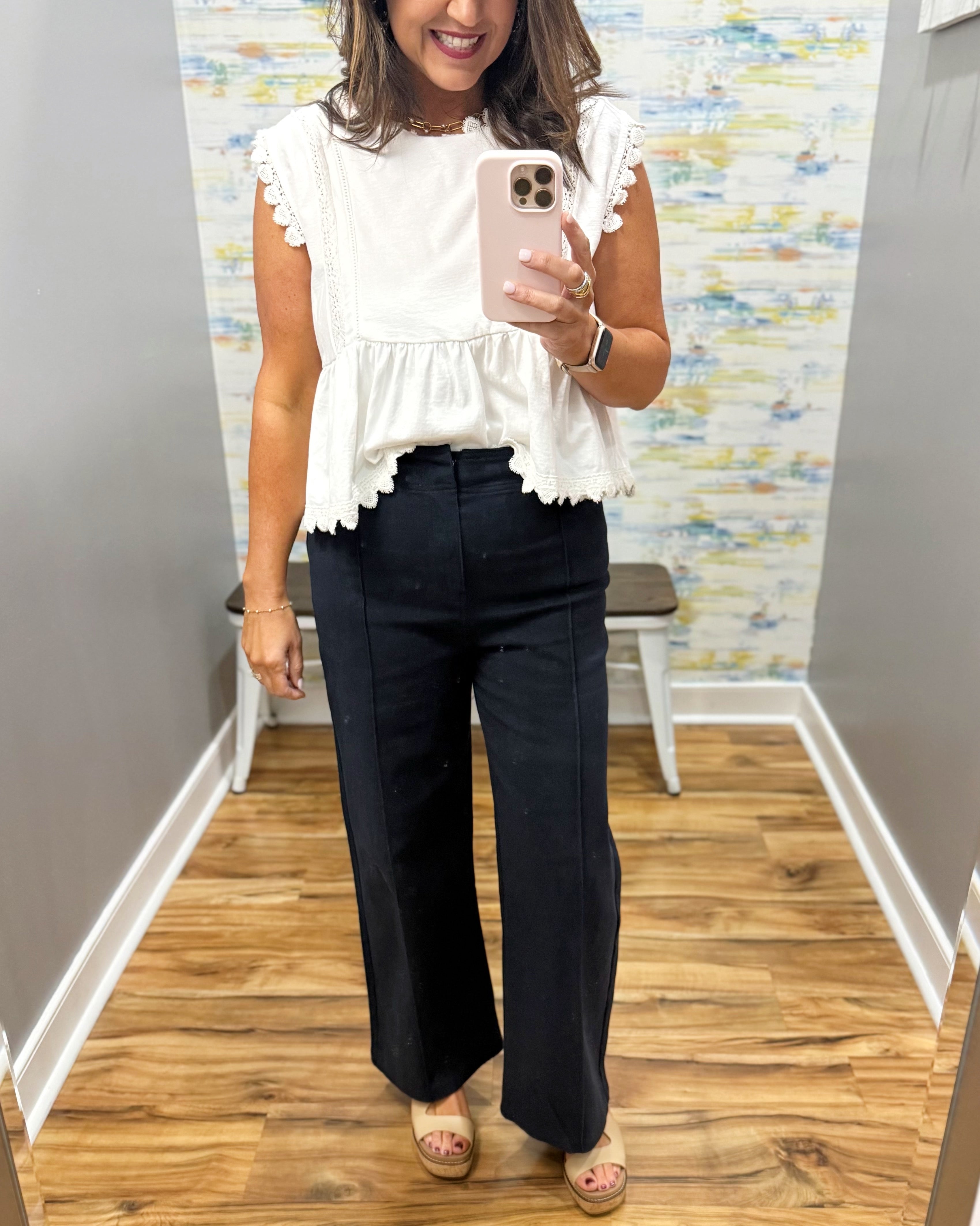 woman wearing navy pants with white top.