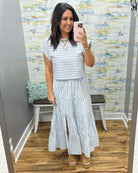 Woman wearing a striped dress in a room with a textured wall.