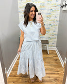 Woman wearing a striped dress in a room with a colorful wall.