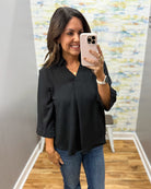 woman wearing a black 3/4 sleeve flowy top.