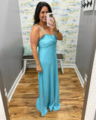 Woman taking a mirror selfie wearing a blue dress in a room with a patterned wall.