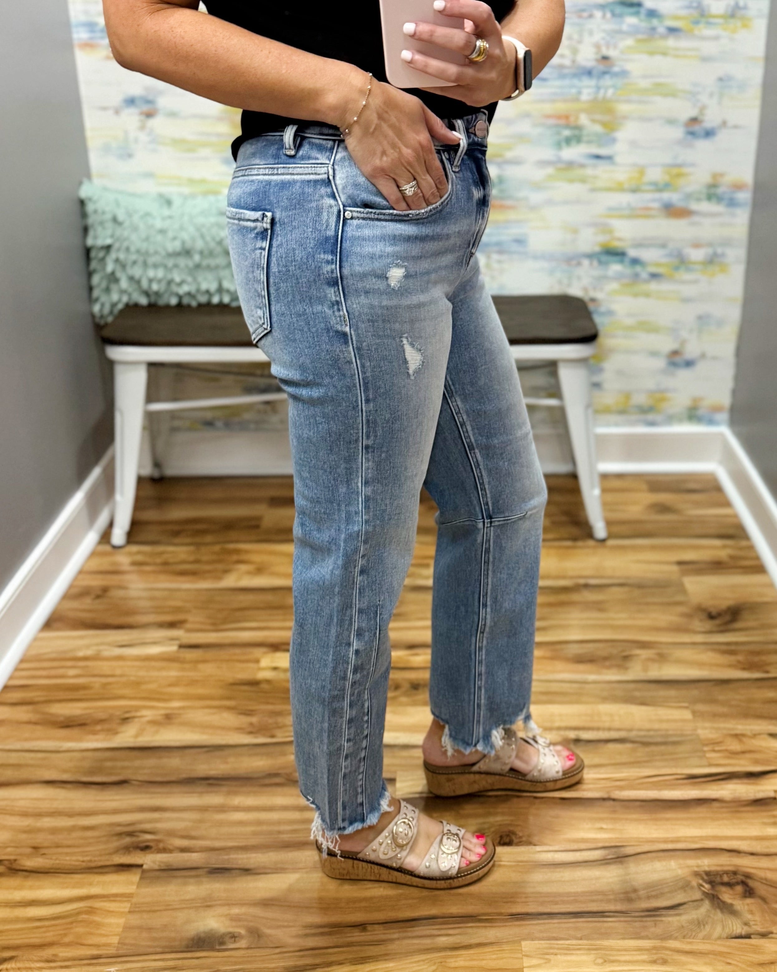 Person wearing blue jeans standing on a wooden floor with a colorful wall in the background