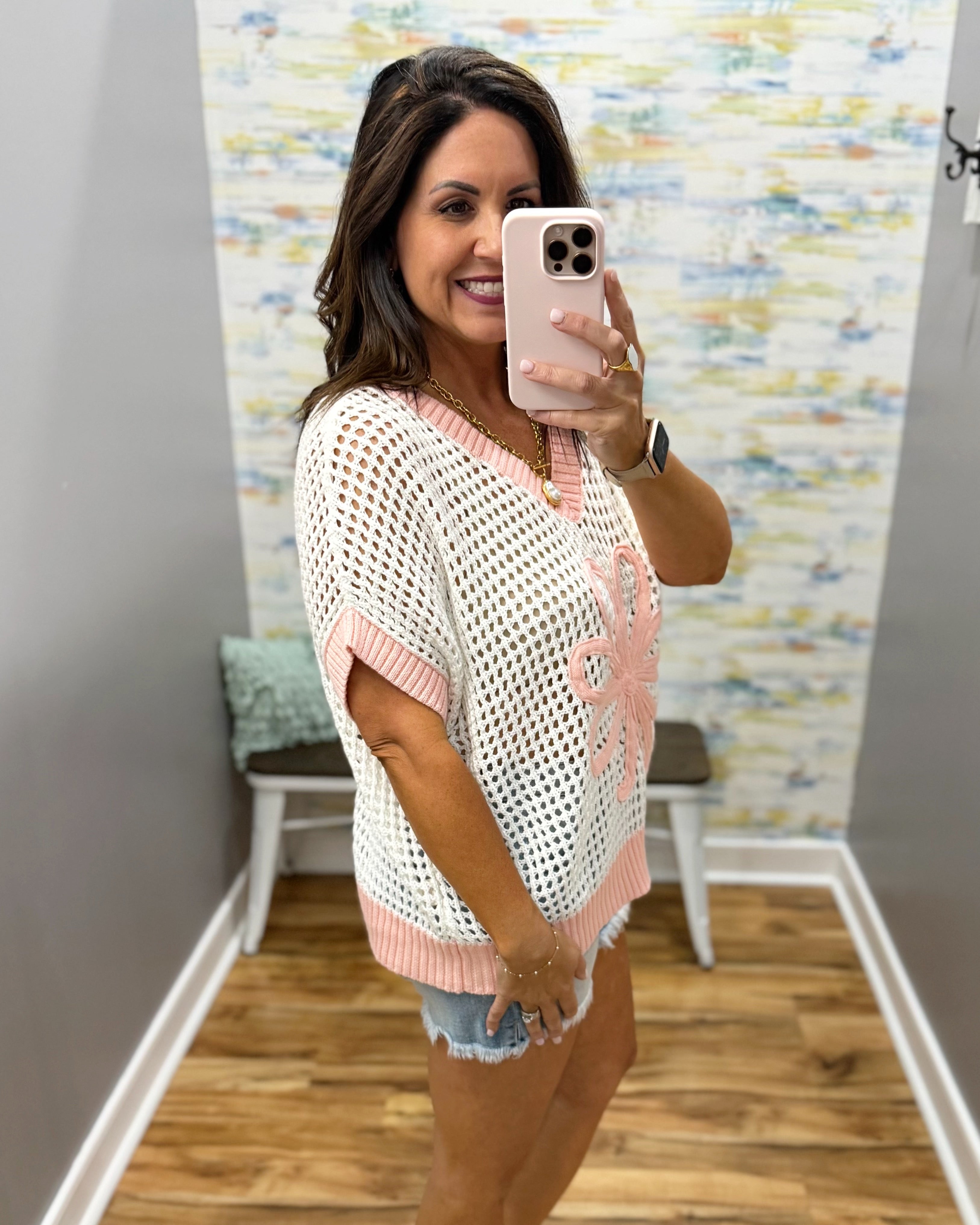 woman wearing a cream crochet knit sweater with pink trim.