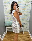 Woman taking a mirror selfie wearing a striped dress in a room with colorful wall paper.