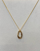 This organic oval open ring pendant necklace features a sculpted elongated oval ring with a molten wavy edge hanging from a fine gold tone chain.
