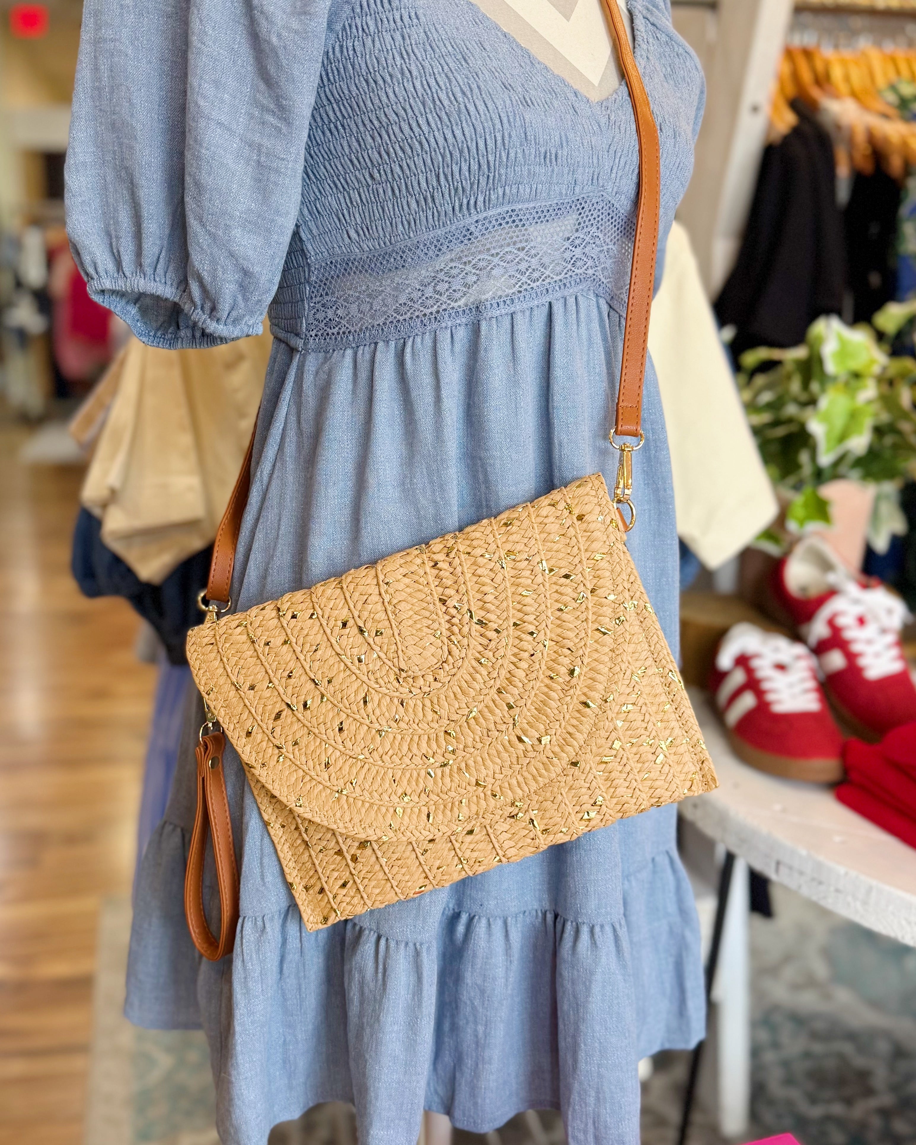 Person wearing a blue dress with a straw handbag in a store setting