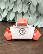 Telettes hair clip on a wooden surface with a textured green wall in the background