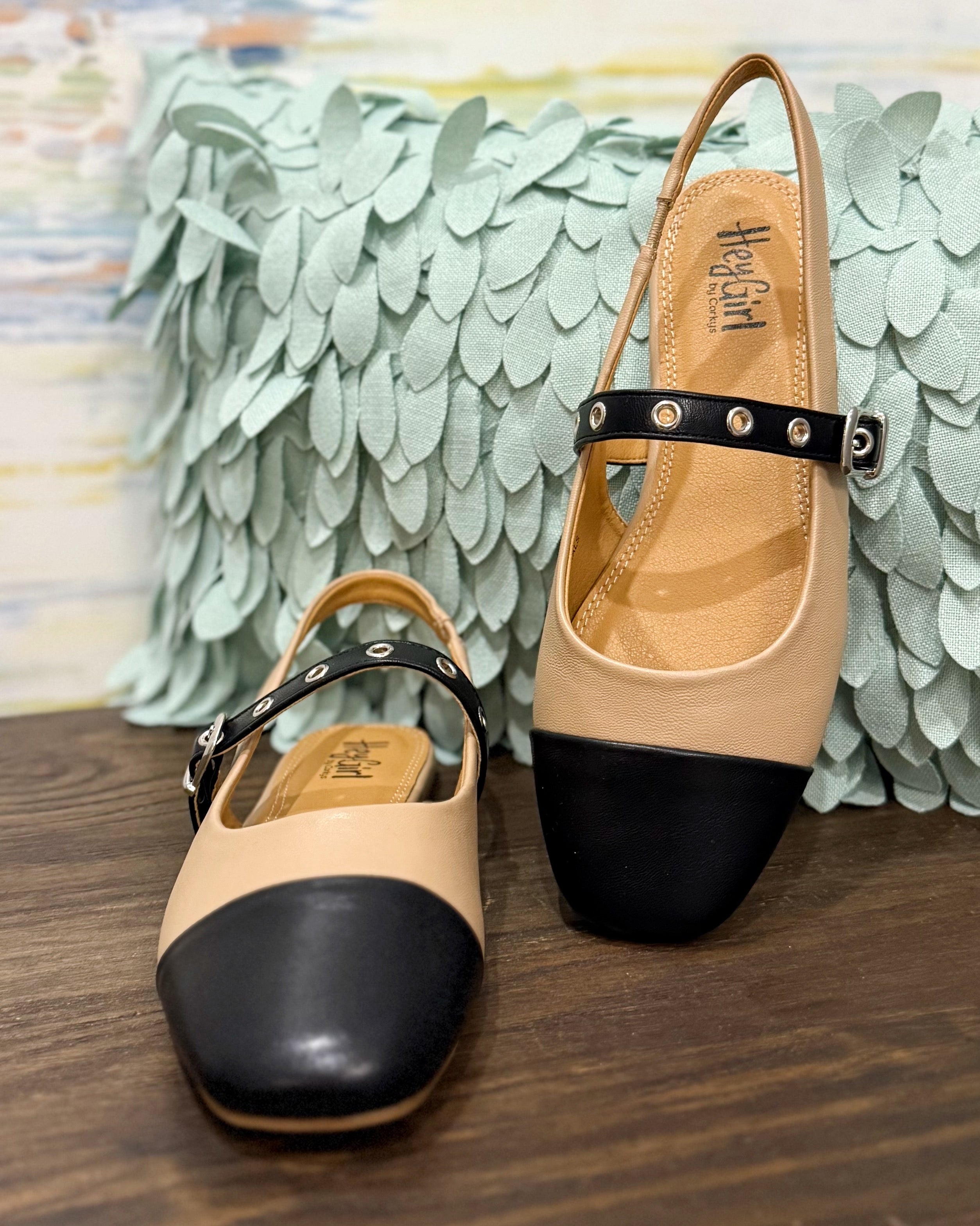 Pair of beige and black shoes with a decorative background