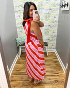Woman wearing a red and pink striped dress in a room with a patterned wall.