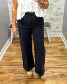 woman wearing navy pants with white top.