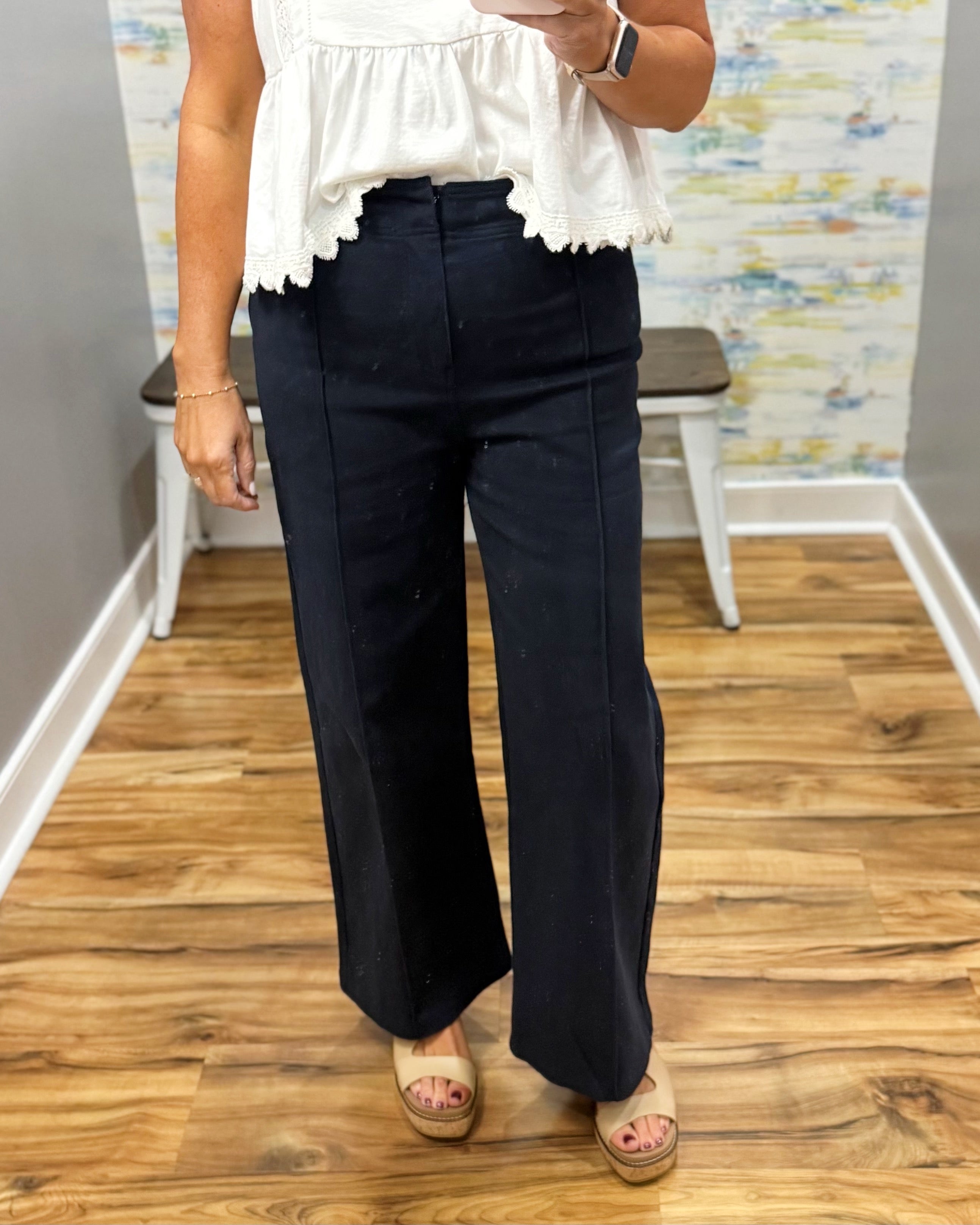 woman wearing navy pants with white top.