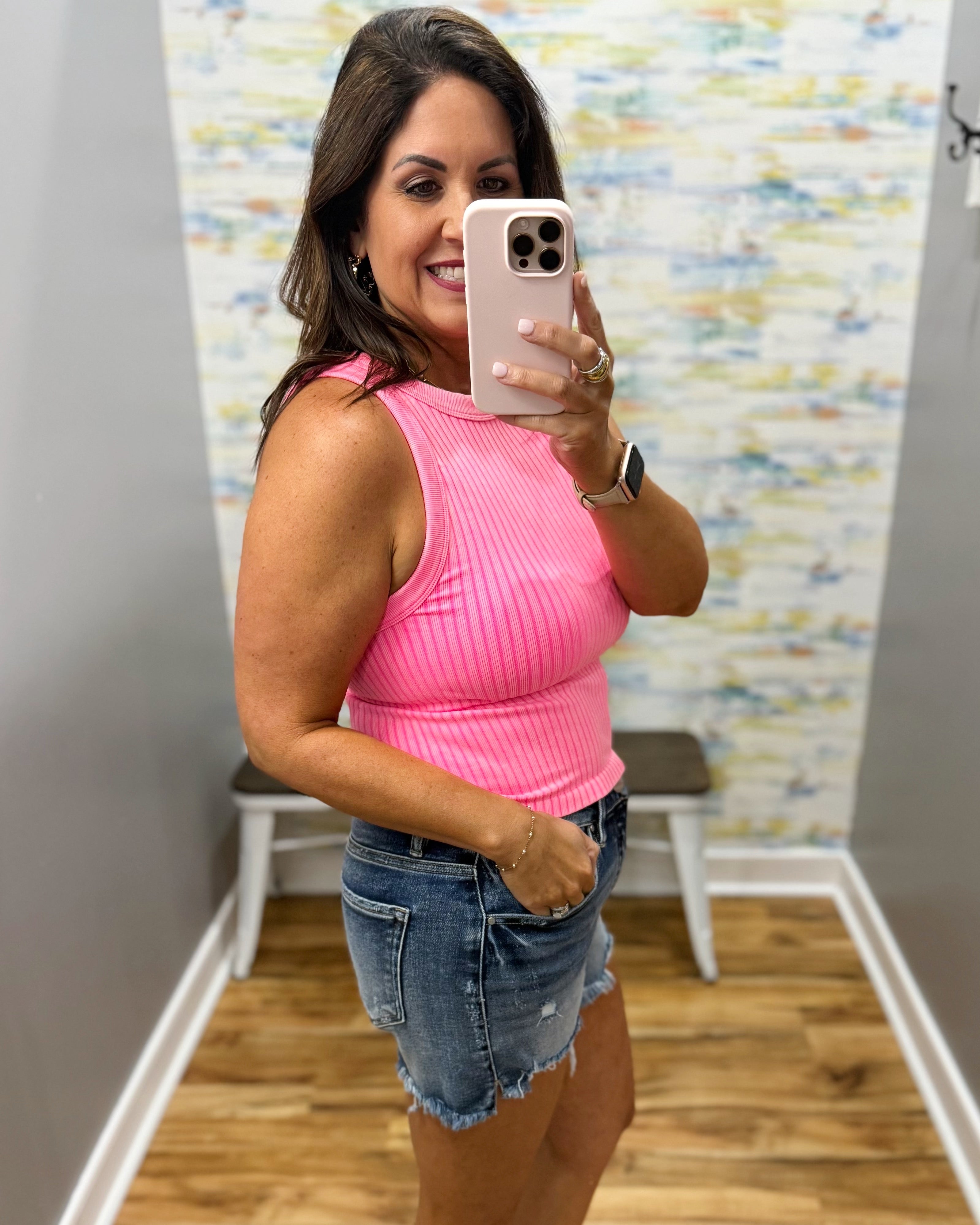 woman wearing neon coral tank with denim shorts.
