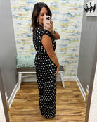 woman taking a selfie wearing a black and white polka dot jumpsuit.