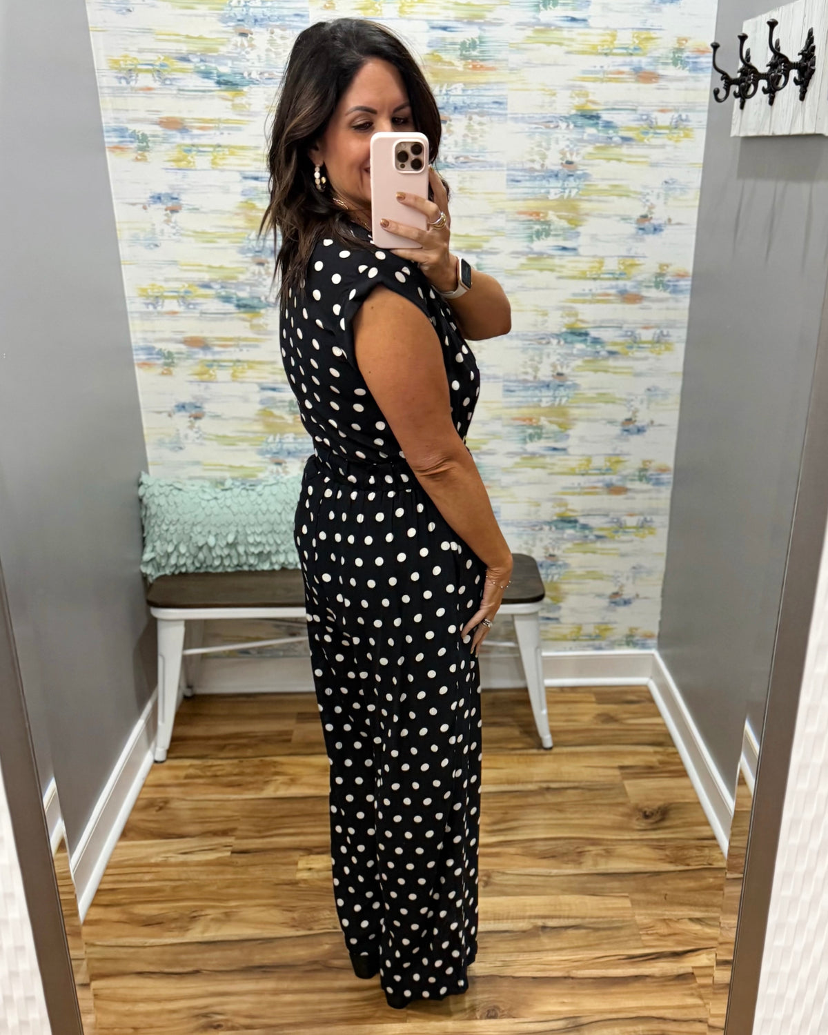 woman taking a selfie wearing a black and white polka dot jumpsuit.