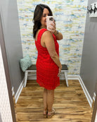 Woman taking a mirror selfie wearing a red dress in a fitting room.