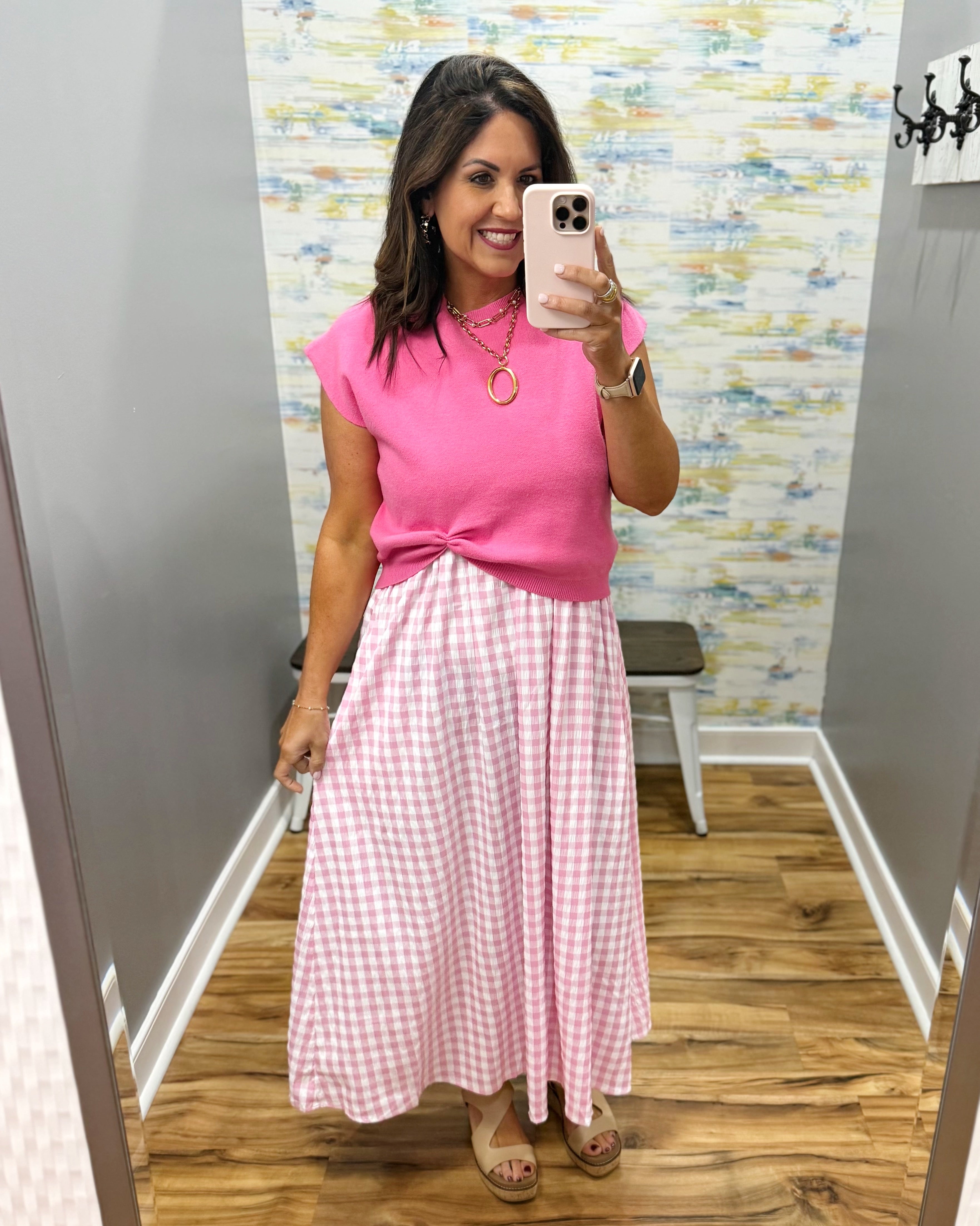 woman wearing gingham print dress in pink with pink sweater over top.