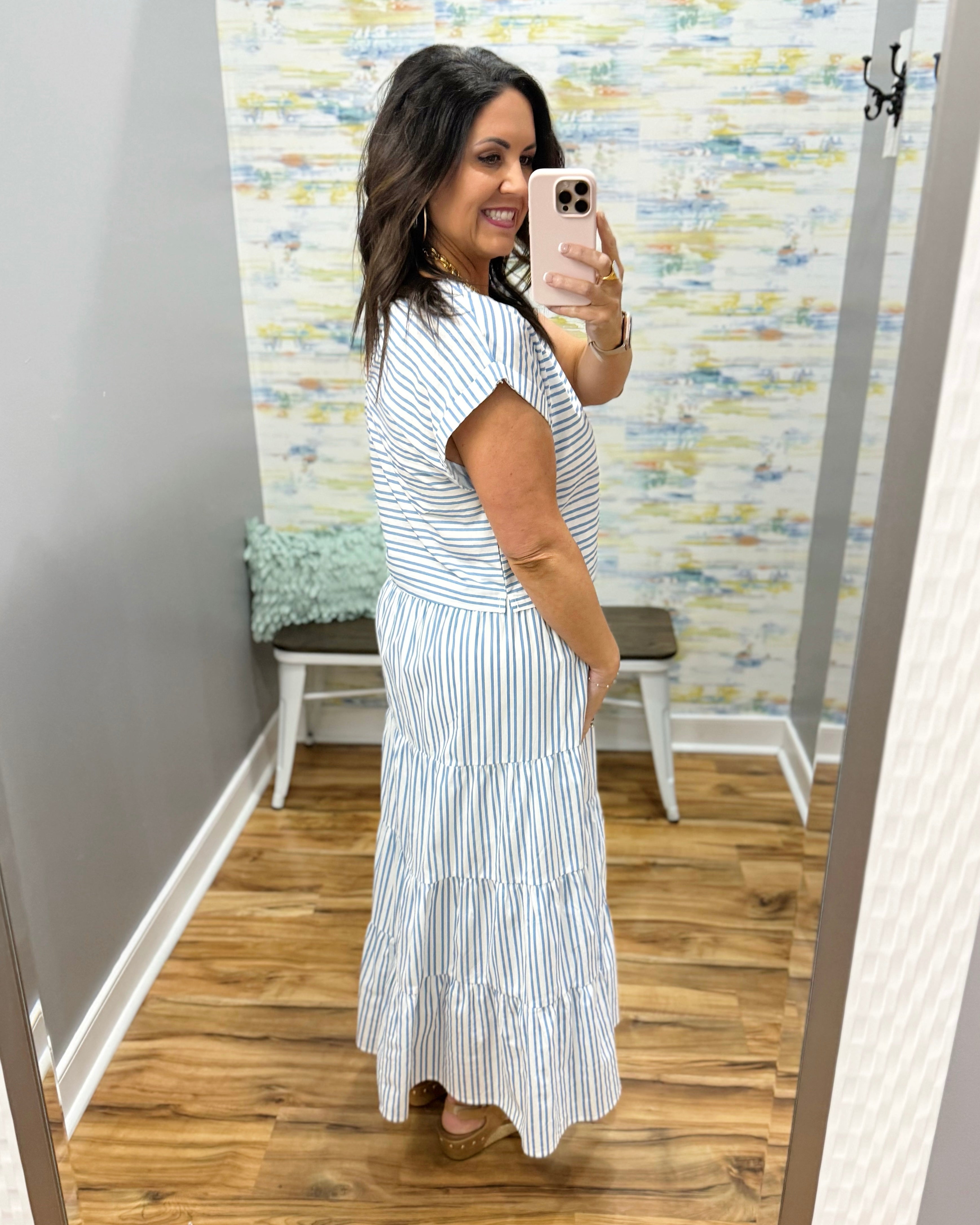 Woman wearing a striped dress in a room with a patterned wall.