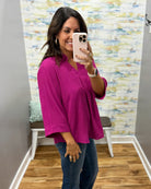 woman wearing a magenta color 3/4 sleeve flowy top.
