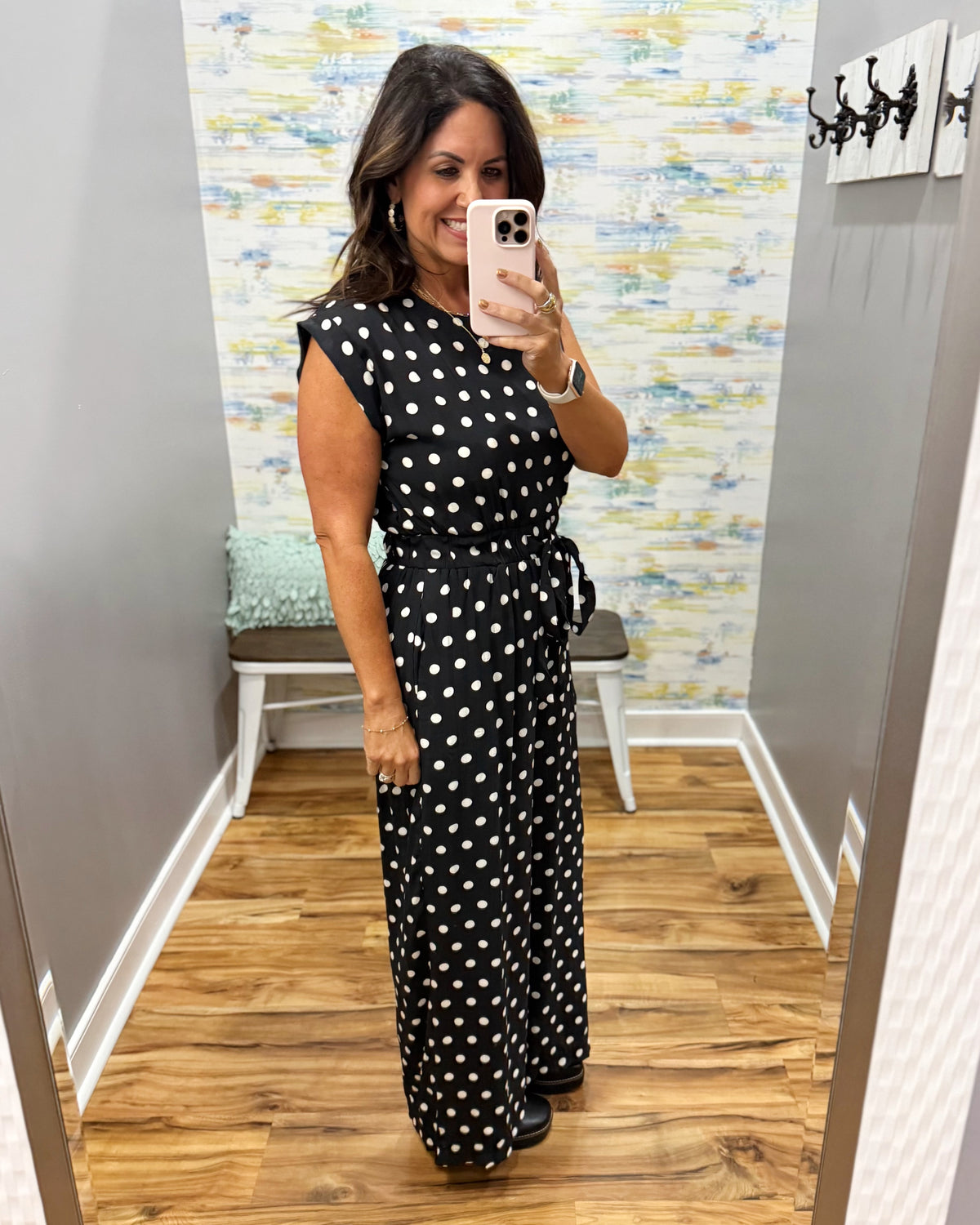woman taking a selfie wearing a black and white polka dot jumpsuit.