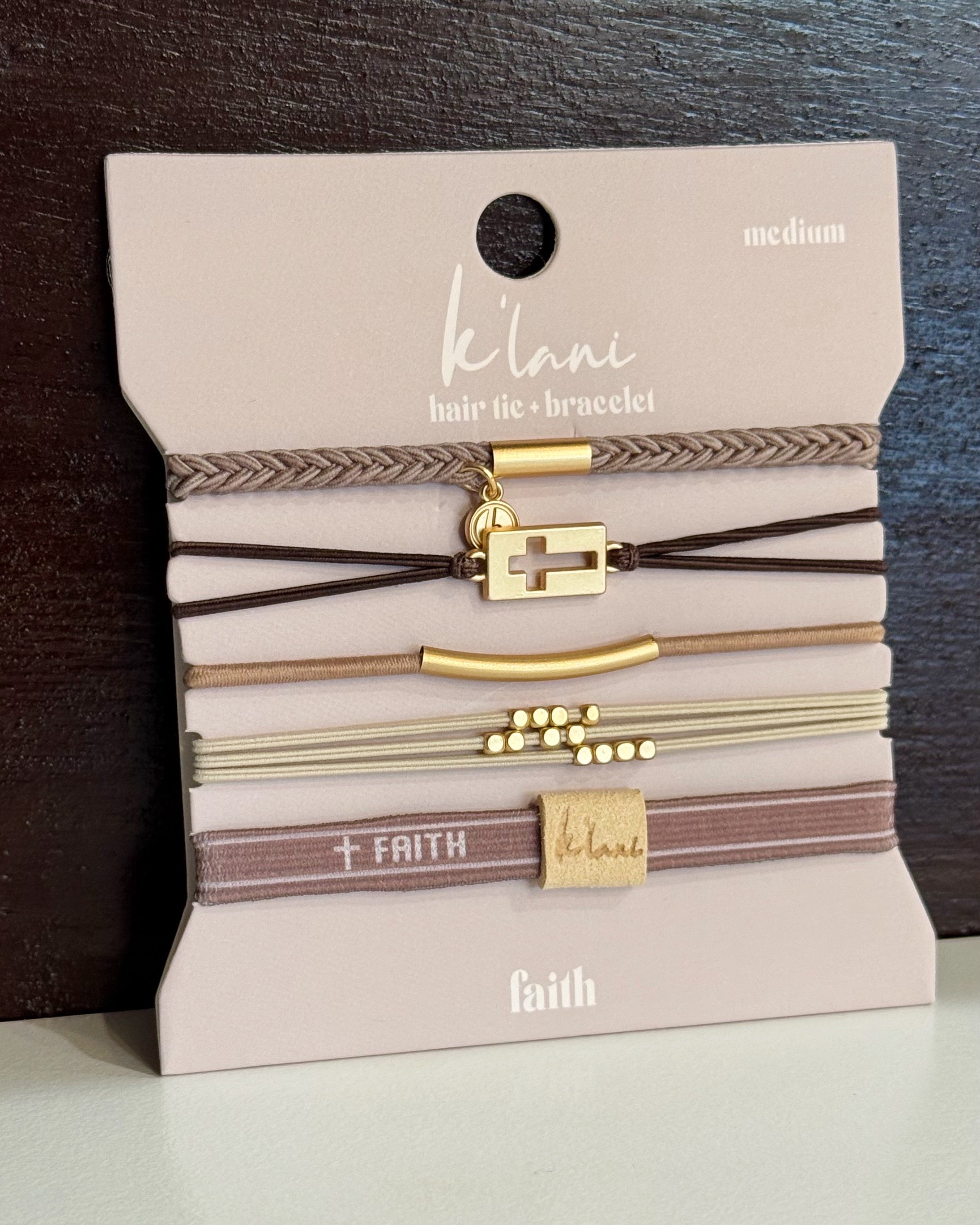 Package of Kelani hair ties and bracelets with gold and brown designs on a neutral background