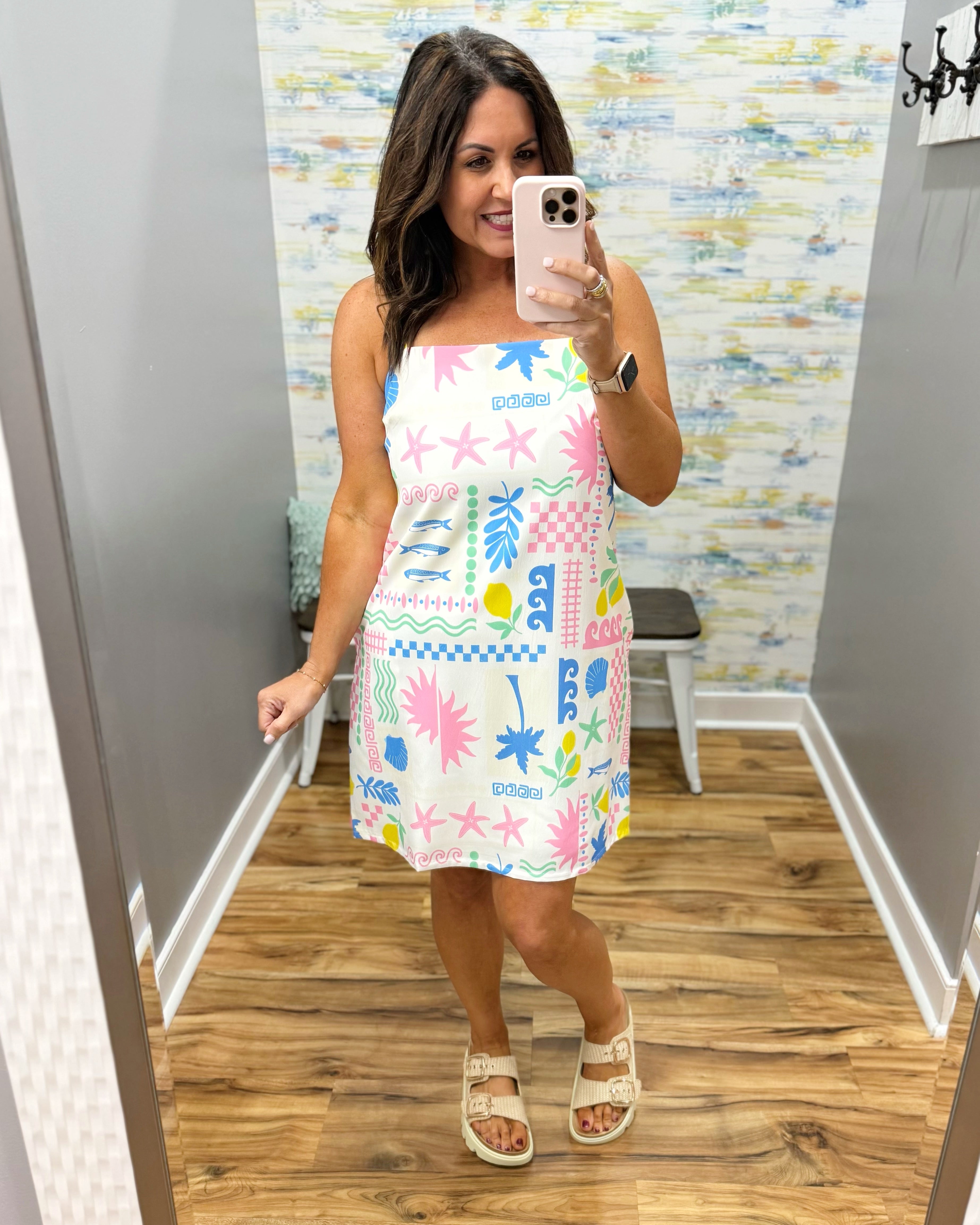 Woman wearing a colorful dress in a room with a patterned wall.