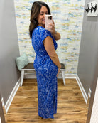 Woman taking a mirror selfie wearing a blue dress in a room with a textured wall.