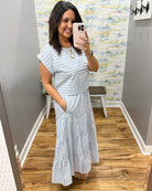 Woman wearing a striped dress in a room with a patterned wall.
