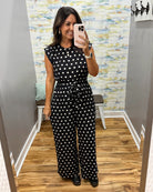 woman taking a selfie wearing a black and white polka dot jumpsuit.