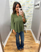 woman wearing a olive 3/4 sleeve flowy top.