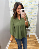 woman wearing a olive 3/4 sleeve flowy top.