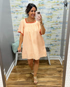 Woman taking a mirror selfie wearing an orange dress in a room with a colorful wall.