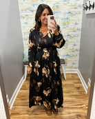 woman wearing a black maxi dress with brown and taupe floral pattern. 