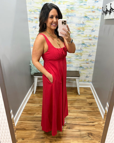 Woman in a red dress in a room with patterned wallpaper.