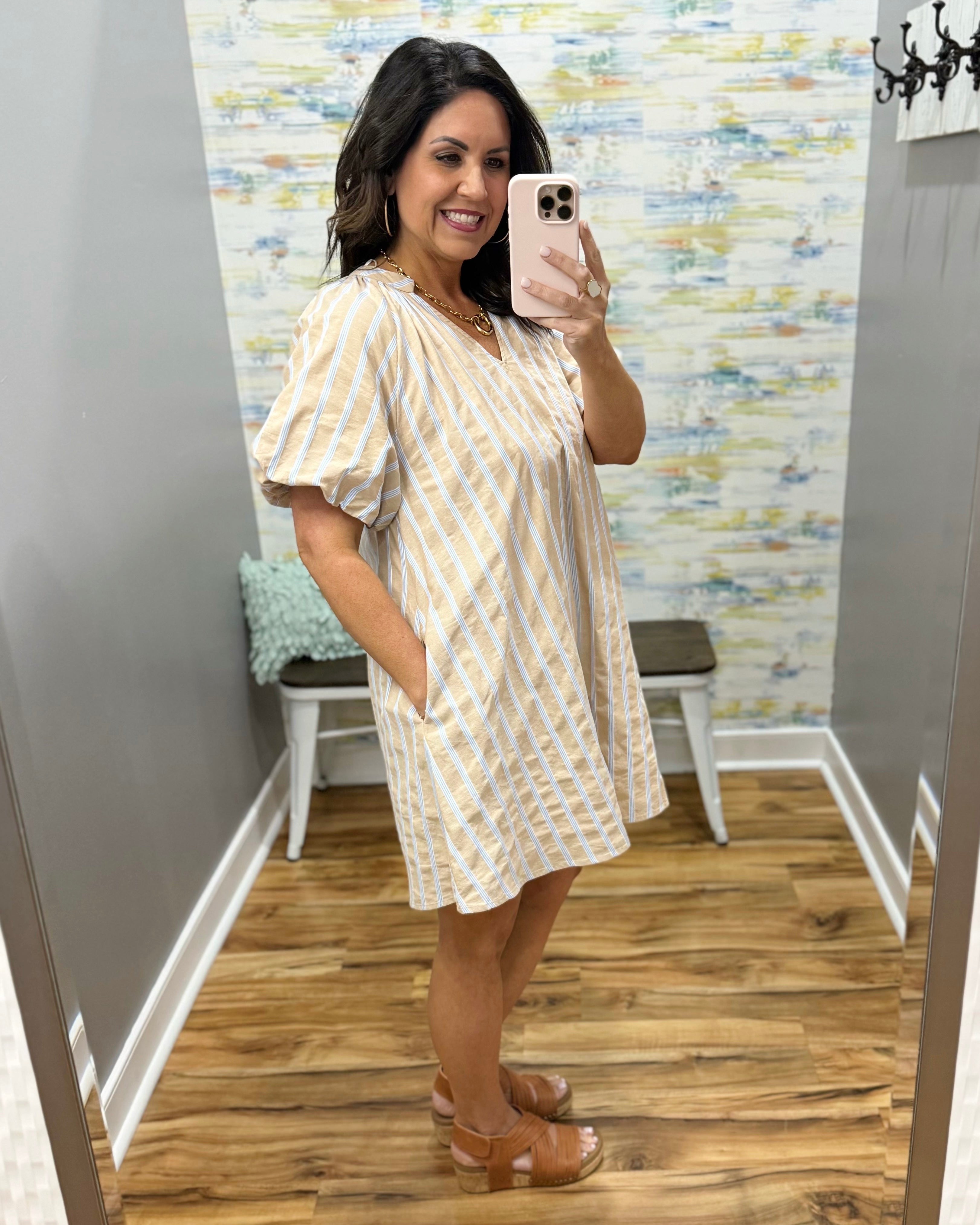 Woman taking a mirror selfie wearing a natural and white striped dress.
