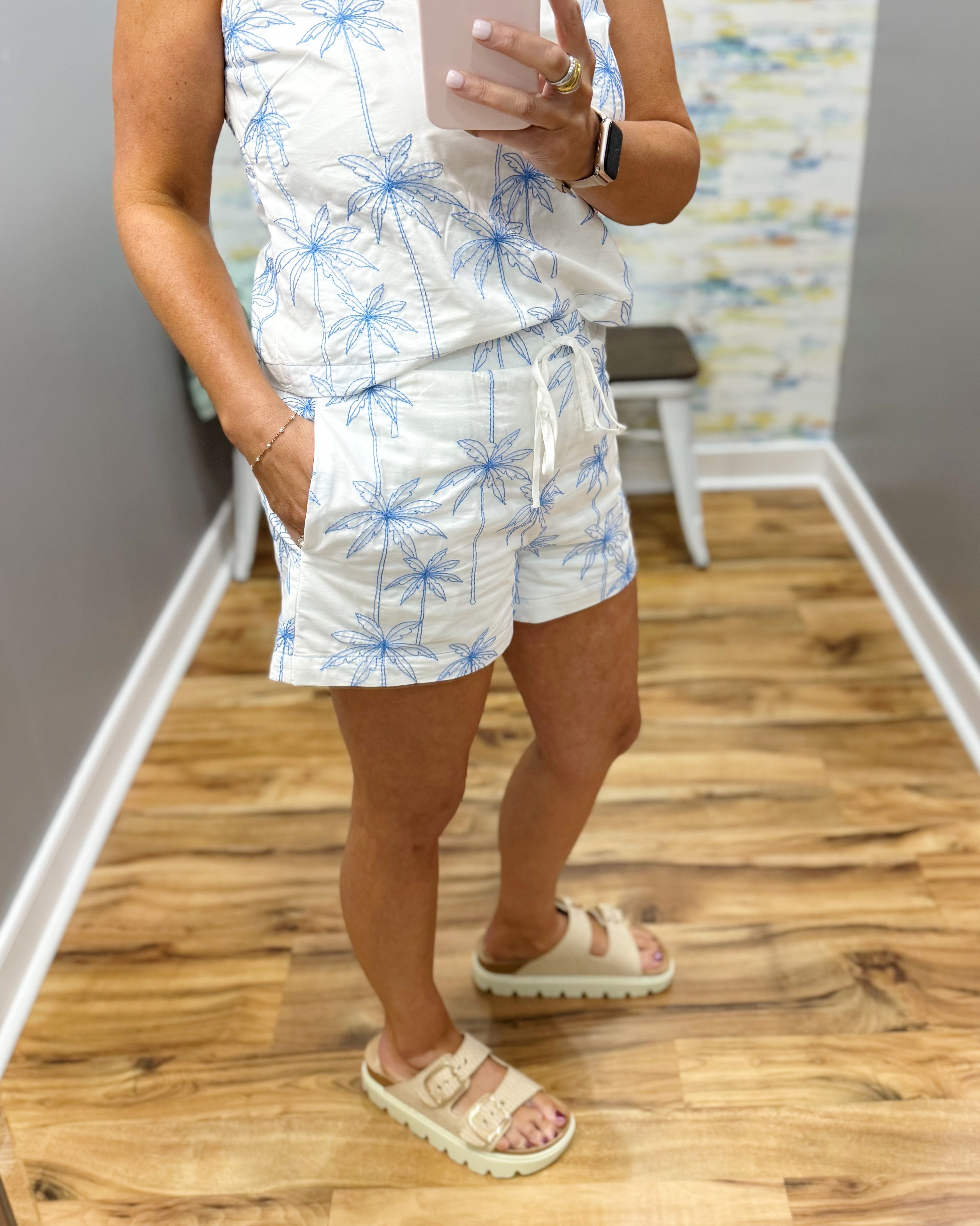 woman wearing shorts with blue palm trees embroidered on them.