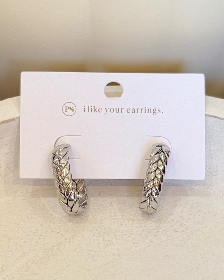 A pair of silver huggie hoop earrings with a textured woven pattern, displayed on a white card that reads 'i like your earrings.' with a small 'ps' logo.