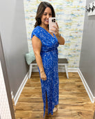 Woman taking a mirror selfie wearing a blue dress with a pattern in a room with a colorful wall.