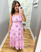 Woman taking a mirror selfie wearing a pink dress with floral patterns in a room.