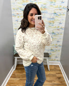 woman taking a selfie wearing a super soft cream sweater with subtle leopard print design. 