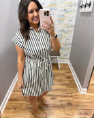 Woman wearing a black and white striped dress in a room with wooden flooring.
