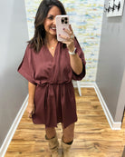 woman taking a selfie wearing a burgundy wrap dress featuring a V-neckline, cinched waist, and flowy short sleeves for a feminine silhouette.