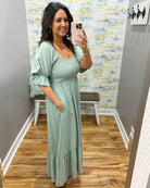 Woman wearing a light green dress in a room with a patterned wall.