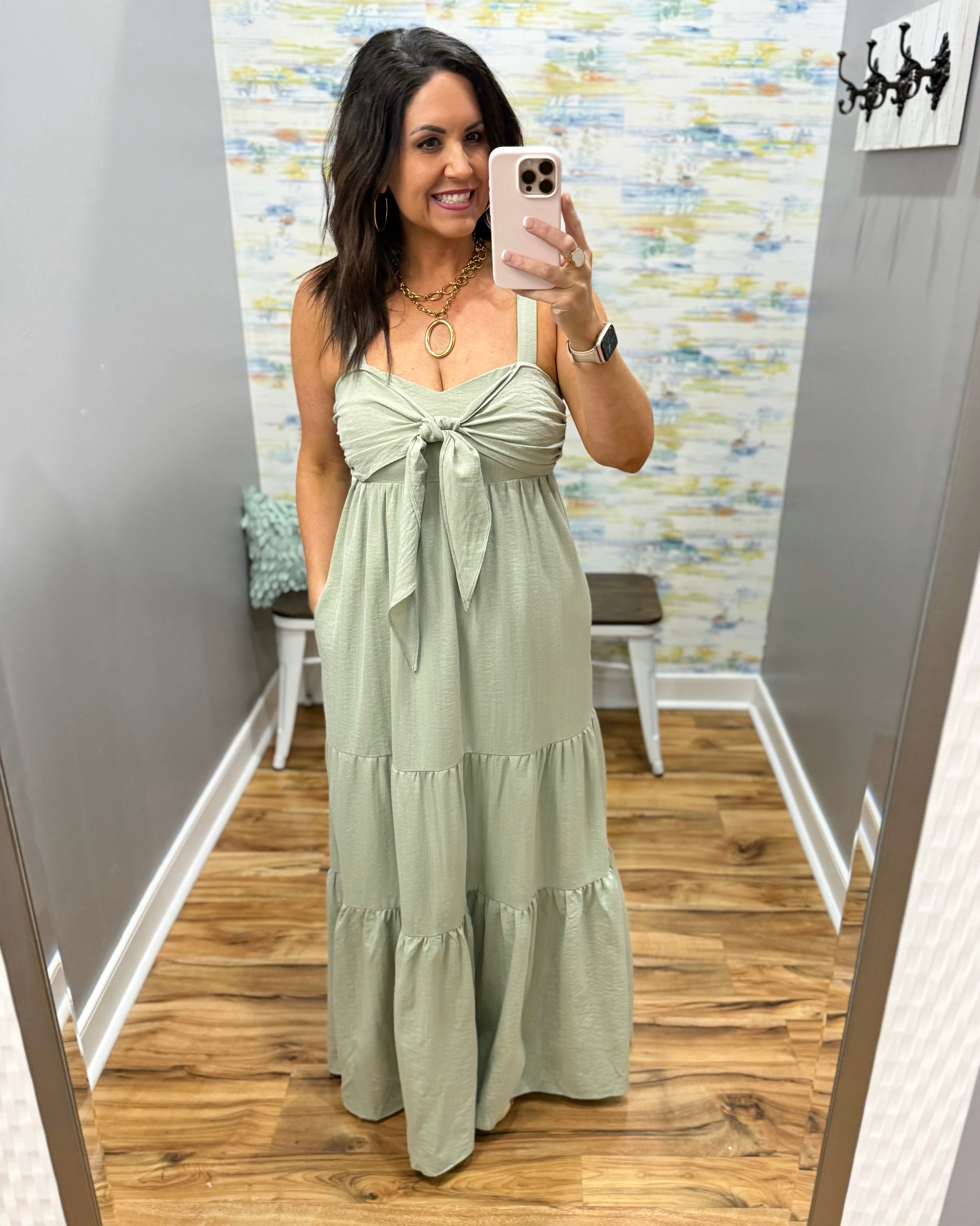 Woman wearing a light green dress in a room with a patterned wall.