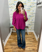 woman wearing a magenta color 3/4 sleeve flowy top with Judy Blue flare jeans in dark wash and Corkys Pity Party wedge shoes in cognac.